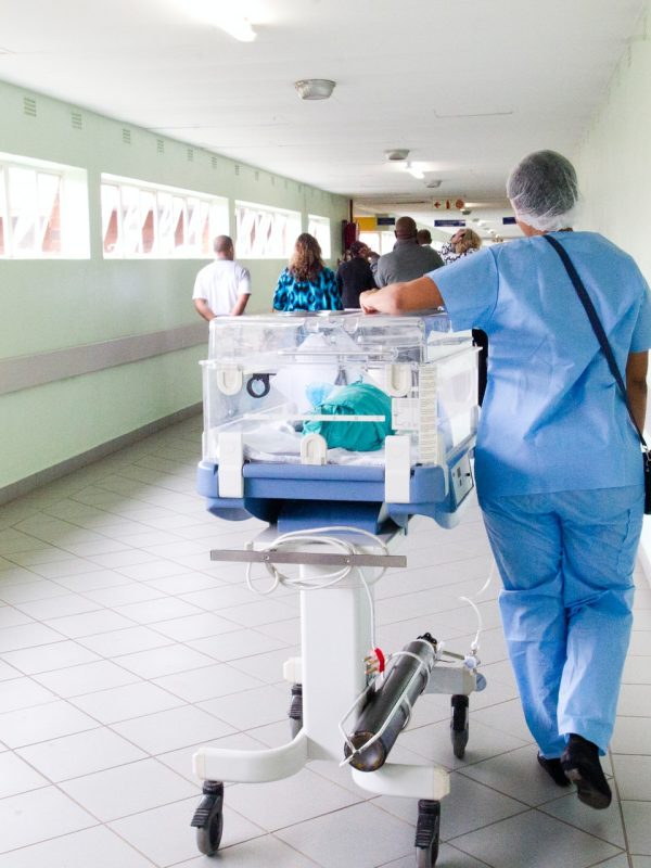 A nurse walks along a hospital hallway while caring for a premature baby